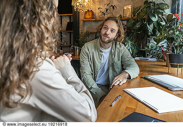 Businessman listening to colleague explaining at cafe