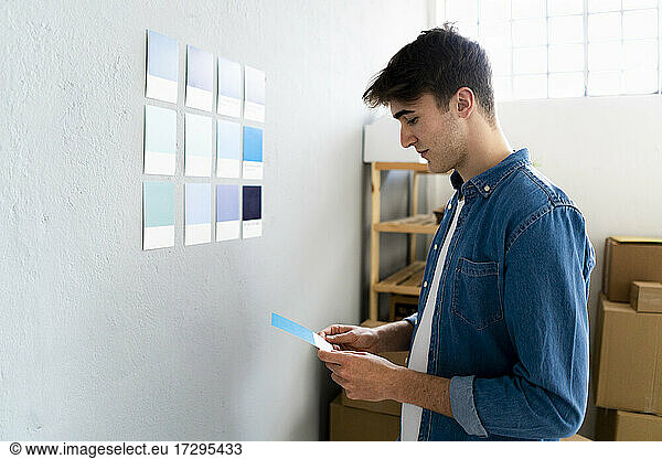 Businessman looking at blue card in front of wall at warehouse