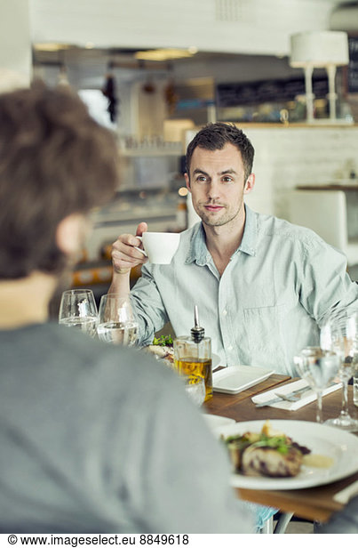 Businessman looking at colleague while having coffee in restaurant