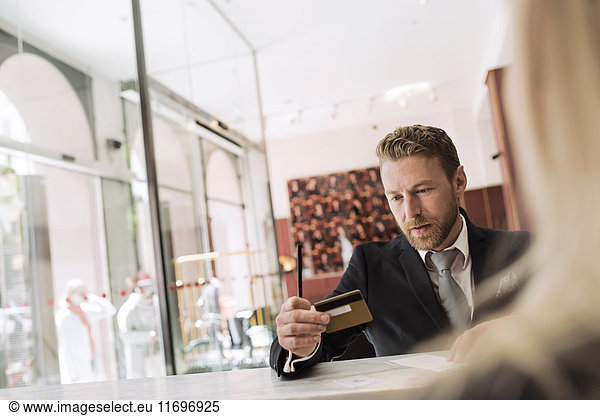 Businessman looking at credit card in hotel reception