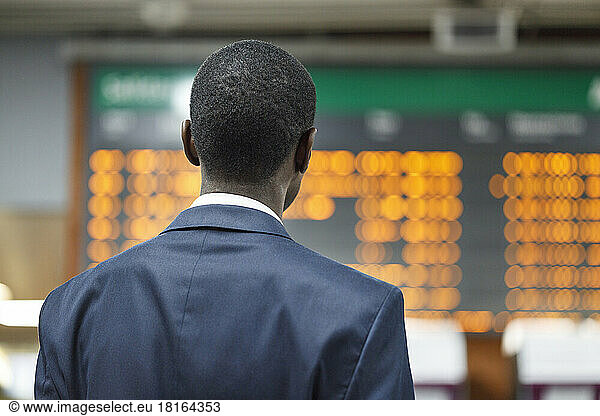 Businessman looking at departure board at railroad station