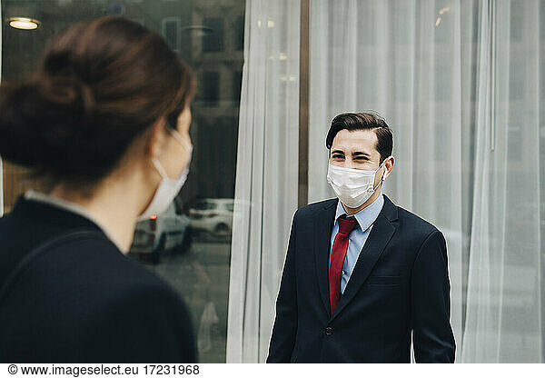 Businessman looking at female colleague outside store during pandemic