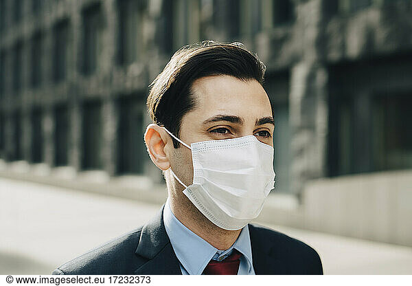 Businessman looking away against office building during pandemic
