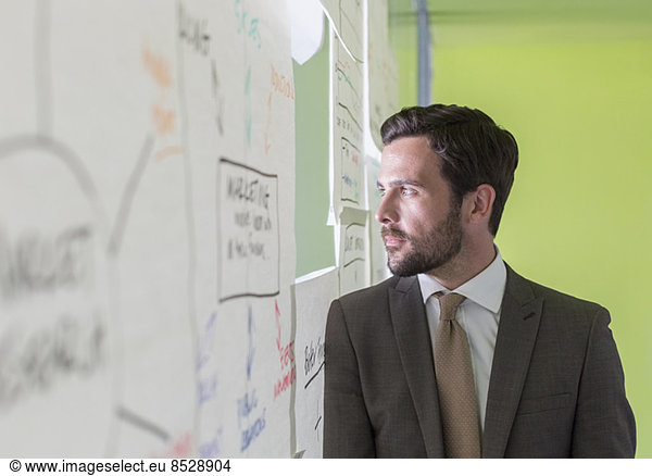 Businessman looking out hole in office window