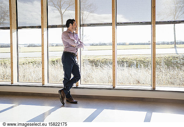 Businessman looking out of window in open-plan office