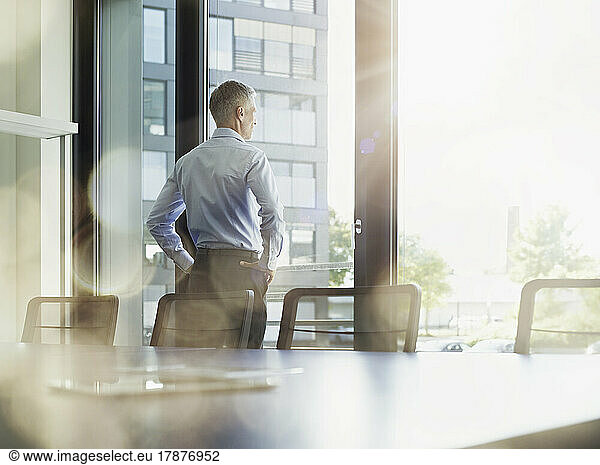 Businessman looking out through window in board room