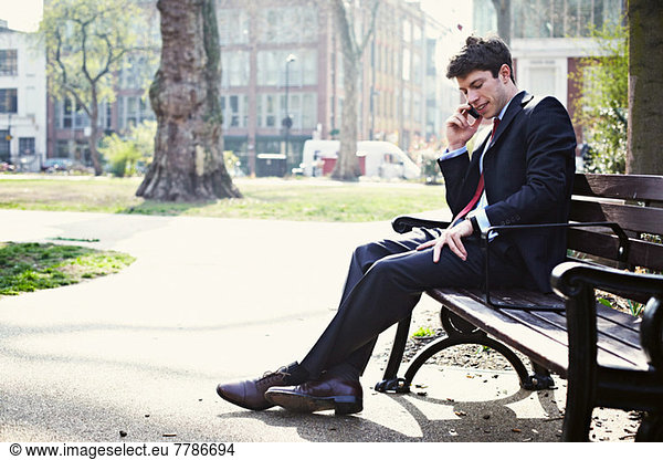 Businessman on park bench on cell phone
