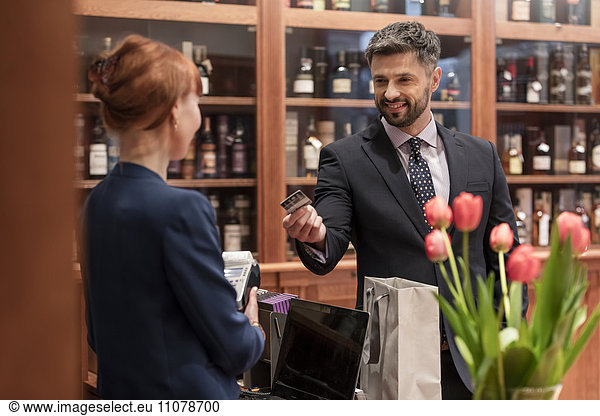 Businessman paying clerk at liquor store counter