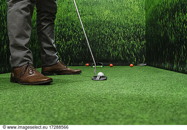 Businessman playing golf on green course at office