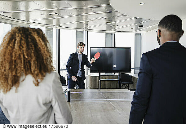 Businessman playing table tennis with colleagues in office