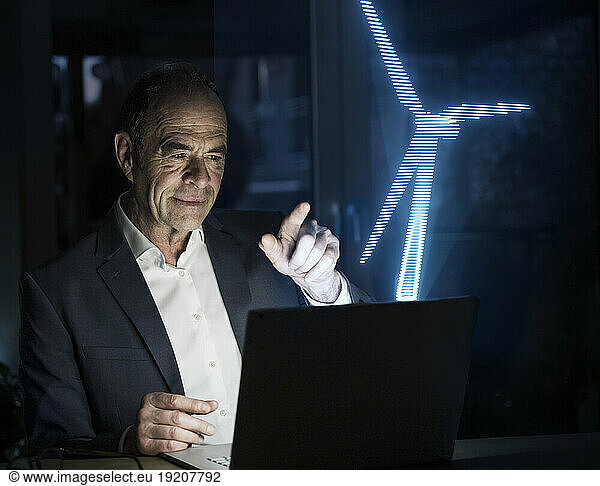 Businessman pointing at futuristic wind turbine in office