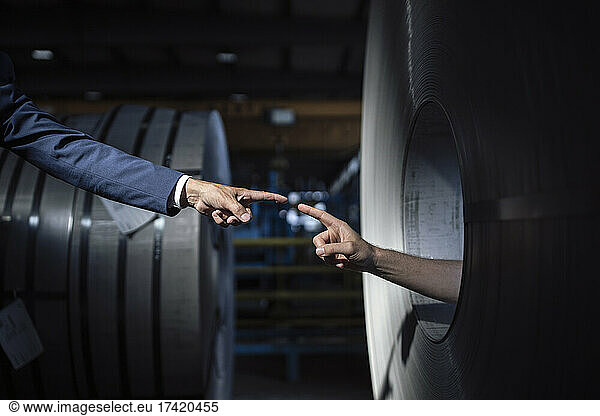 Businessman pointing at hand inside metal sheet roll