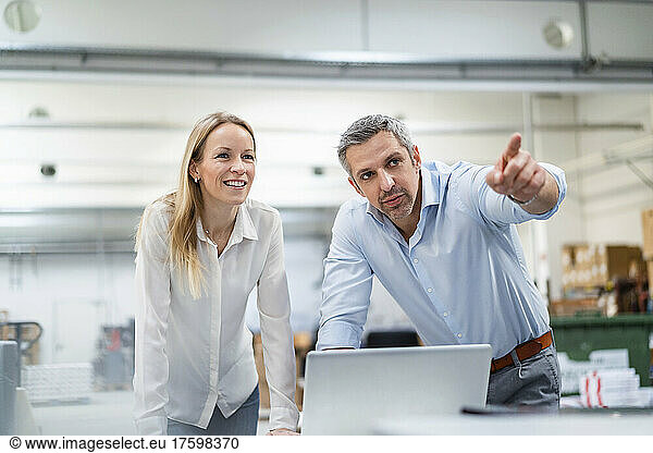 Businessman pointing away by blond businesswoman in industry