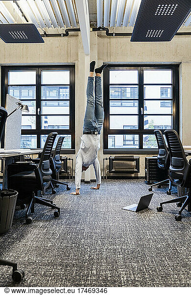 Businessman practicing handstand at workplace