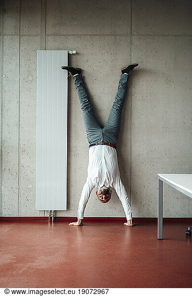Businessman practicing handstand in office
