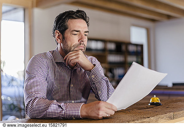 Businessman reading document in wooden open-plan office