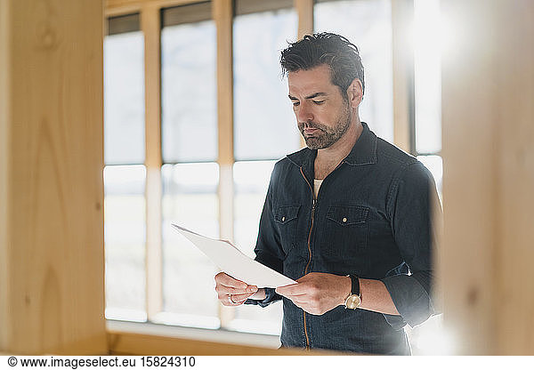 Businessman reading document in wooden open-plan office