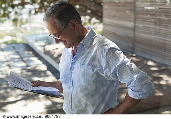 Businessman reading papers outdoors