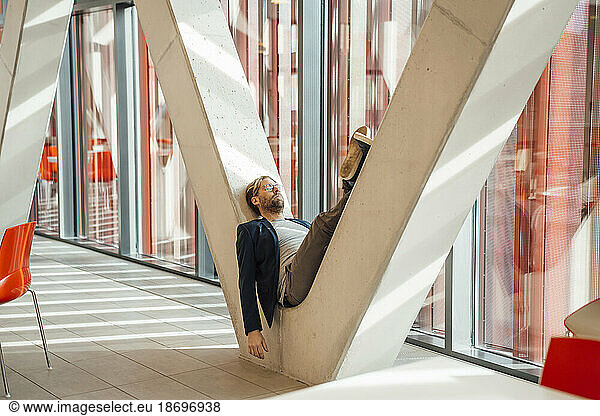 Businessman relaxing on V-shaped column in building