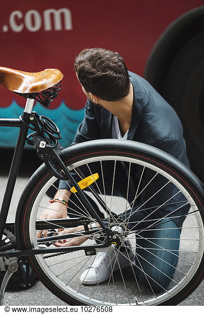 Businessman repairing bicycle on street