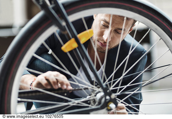 Businessman repairing bicycle tire on street