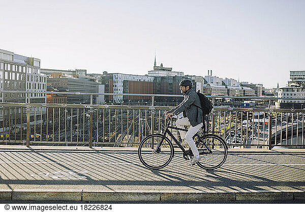 Businessman riding bicycle on cycling path against buildings in city