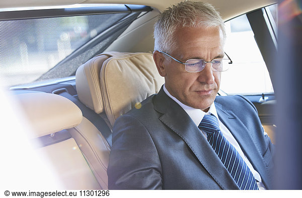 Businessman riding in back seat of town car