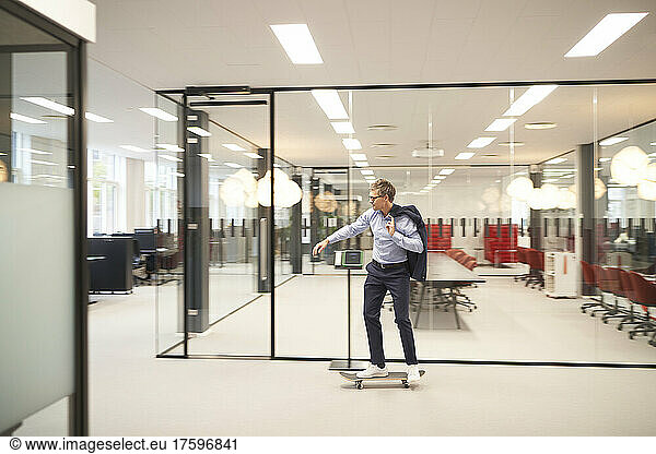 Businessman riding skateboard in modern office