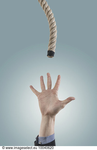 Businessman's hand reaching for a rope for salvation  Bavaria  Germany