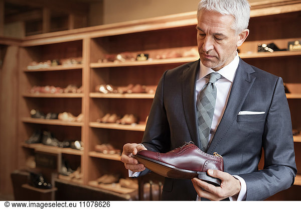 Businessman shopping for dress shoes in menswear shop
