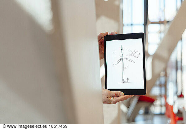 Businessman showing drawing of wind turbine on tablet PC in office