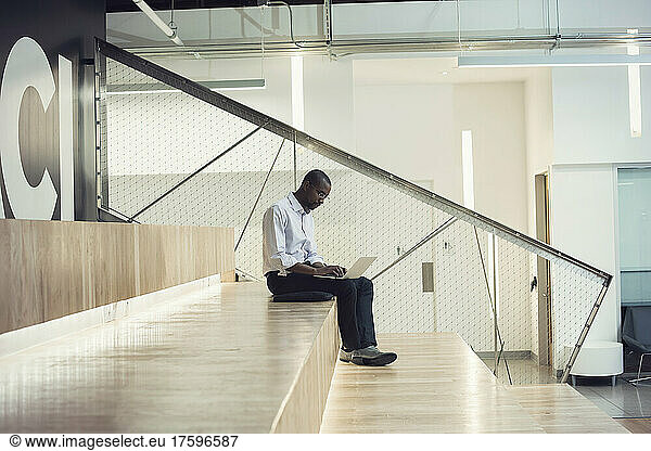 Businessman sitting on stairs using laptop