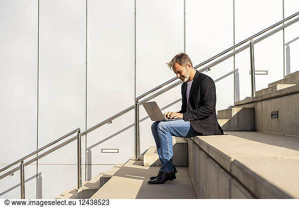Businessman sitting on steps outdoors using laptop