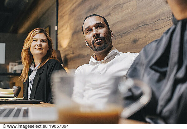 Businessman sitting with female colleagues at conference table in board room during meeting
