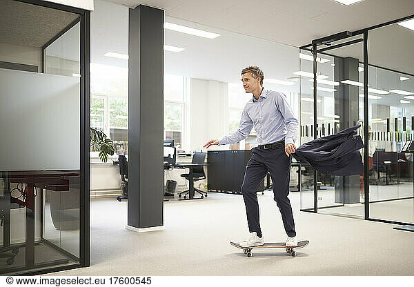 Businessman skateboarding in modern office