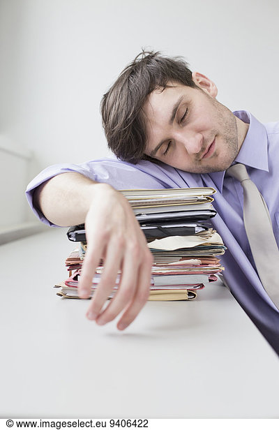 Businessman sleeping on stack of files in office