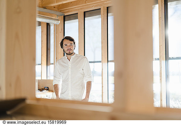 Businessman standing at the window in wooden open-plan office