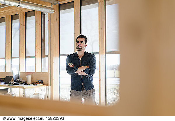 Businessman standing at the window in wooden open-plan office