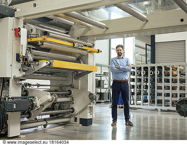 Businessman standing by machinery in industry