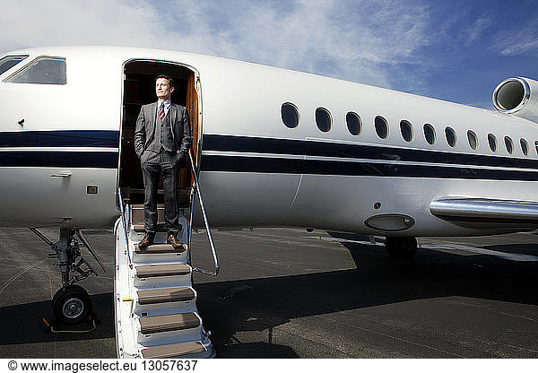 Businessman standing on steps of corporate jet