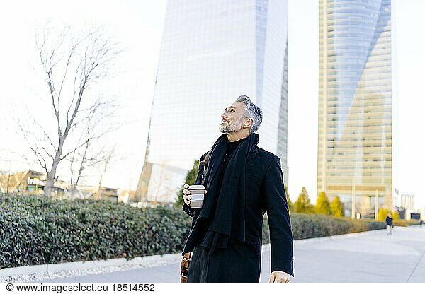 Businessman standing with coffee cup at footpath