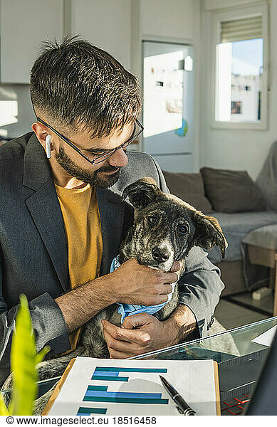 Businessman stroking pet dog at home office