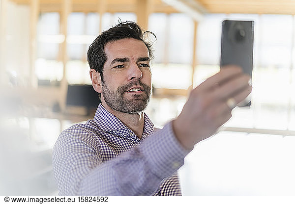 Businessman taking a selfie in wooden open-plan office