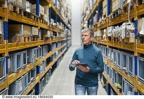 Businessman taking inventory holding tablet PC in warehouse