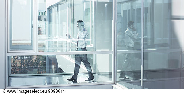 Businessman talking on cell phone in office corridor