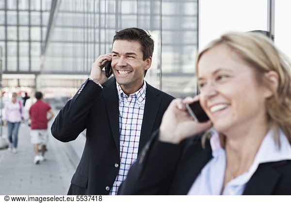 Businessman talking on mobile phone with woman colleague in front