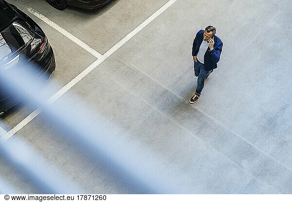 Businessman talking on smart phone walking in parking lot