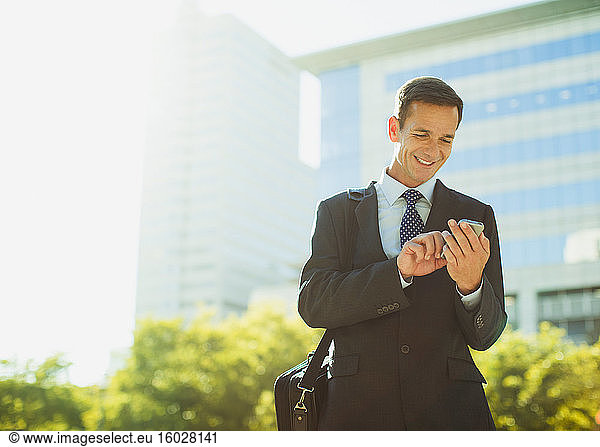 Businessman text messaging outside urban building