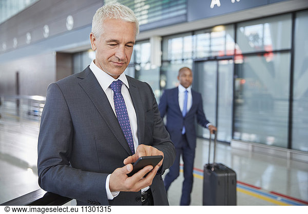 Businessman texting with cell phone in airport concourse