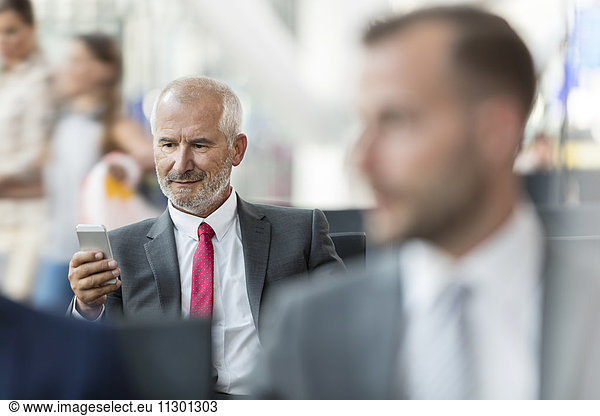 Businessman texting with cell phone in airport departure area
